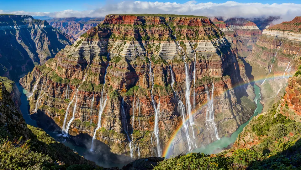 何層もの地層の壁から段になって落ちる無数の滝と、谷底の霧と虹